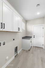 Laundry area with washer hookup, electric dryer hookup, cabinets, and light wood-type flooring