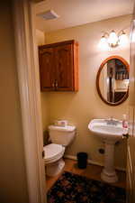 Bathroom with toilet, a textured ceiling, and hardwood / wood-style flooring