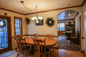 Dining room featuring crown molding, an inviting chandelier, wood-type flooring, and a baseboard heating unit