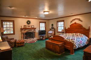 Bedroom with carpet, ornamental molding, a fireplace, and a textured ceiling