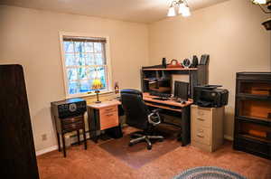 Office area with dark colored carpet, baseboard heating, and an inviting chandelier