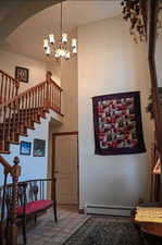 Stairs with baseboard heating, tile patterned floors, and an inviting chandelier