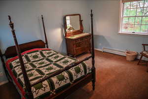 Bedroom with carpet flooring and a baseboard radiator