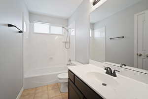 Full bathroom featuring toilet, vanity, shower / bath combination, and tile patterned floors