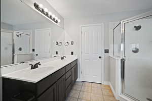 Bathroom featuring tile patterned flooring, vanity, and an enclosed shower