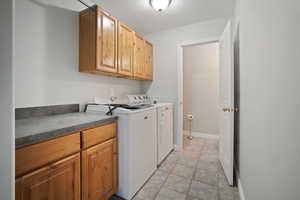 Clothes washing area featuring washer and clothes dryer and cabinets