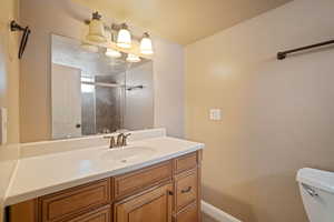 Bathroom with an enclosed shower, vanity, toilet, and a textured ceiling