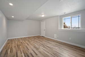 Empty room featuring a textured ceiling and light hardwood / wood-style flooring