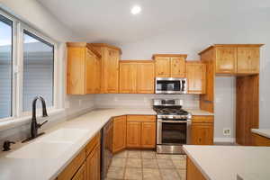 Kitchen featuring sink, lofted ceiling, stainless steel appliances, and light tile patterned floors