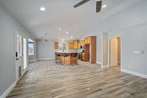 Kitchen featuring ceiling fan, a center island, stainless steel appliances, a kitchen breakfast bar, and light hardwood / wood-style floors