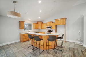 Kitchen featuring a breakfast bar, a center island, sink, vaulted ceiling, and appliances with stainless steel finishes