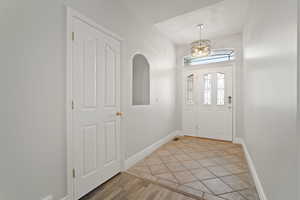 Foyer entrance with light hardwood / wood-style flooring and a notable chandelier