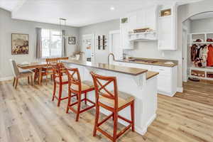 Kitchen featuring white cabinets, pendant lighting, and a kitchen island with sink