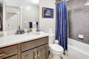 Full bathroom with toilet, vanity, and shower / tub combo with curtain