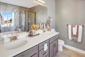 Bathroom featuring tile patterned flooring, vanity, toilet, and a shower with shower door