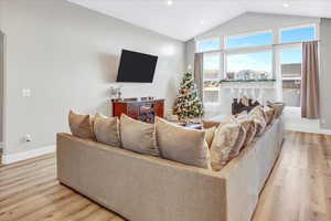 Living room with light hardwood / wood-style floors and vaulted ceiling