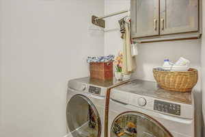 Washroom with washer and clothes dryer and cabinets