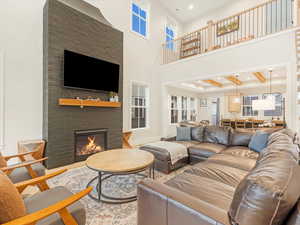 Living room featuring a fireplace, beam ceiling, a towering ceiling, and wood-type flooring