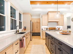 Kitchen featuring light brown cabinets, sink, appliances with stainless steel finishes, decorative light fixtures, and light hardwood / wood-style floors