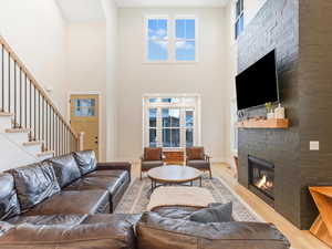 Living room with a towering ceiling, light hardwood / wood-style flooring, a wealth of natural light, and a stone fireplace