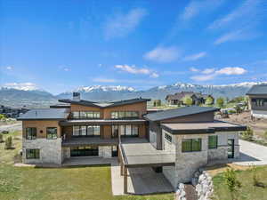 Back of property featuring stone siding, a mountain view, and a large entertaining patio