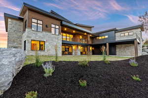 Back of property featuring a balcony and stone siding, gorgeous landscaping