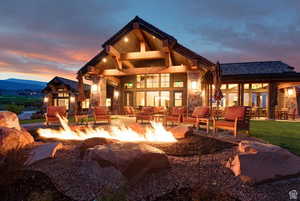 Back house at dusk featuring an outdoor living space with a fire pit