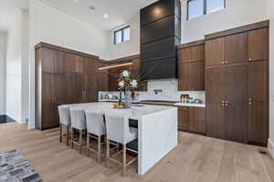 Kitchen featuring a towering ceiling, modern cabinets, waterfall natural stone island