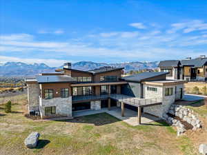 Rear view of property with a mountain view, a patio area, and a lawn