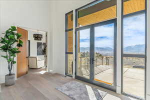 Doorway to outside featuring a mountain view, expansive windows, and a healthy amount of sunlight