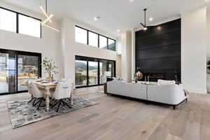 Living room featuring a towering ceiling, ornamental molding, inviting chandelier, and a fireplace