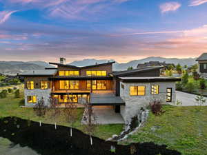 Back of property at dusk with stone siding, a mountain view, a chimney, and a standing seam roof