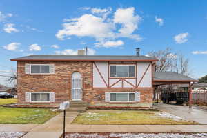 View of front facade featuring a front yard and a carport