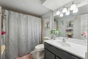 Bathroom featuring vanity, curtained shower, and toilet