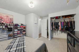 Carpeted bedroom with a closet and a textured ceiling