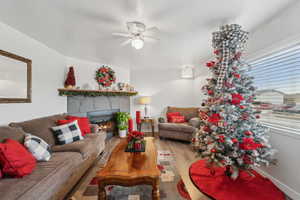 Living room featuring ceiling fan, light hardwood / wood-style floors, and a tiled fireplace