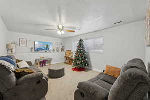 Living room featuring ceiling fan, carpet, and a textured ceiling