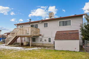 Rear view of house featuring a deck, a yard, and central AC