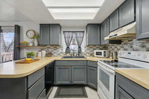 Kitchen featuring gray cabinets, white appliances, and sink