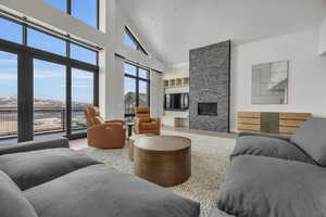 Living room featuring hardwood / wood-style floors, a towering ceiling, and a stone fireplace