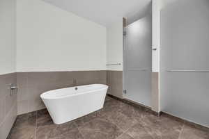 Bathroom featuring a washtub and tile walls