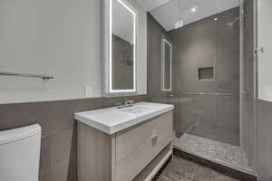 Bathroom with vanity, toilet, and a shower with shower door