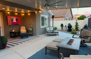 Patio terrace at dusk featuring ceiling fan and an outdoor living space with a fire pit