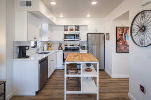 Kitchen featuring white cabinets, decorative backsplash, stainless steel appliances, and sink