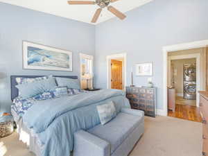 Bedroom with ceiling fan, light carpet, and stacked washer and clothes dryer