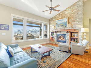 Living room with a stone fireplace, a mountain view, lofted ceiling, and hardwood / wood-style flooring