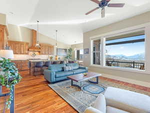 Living room with a mountain view, lofted ceiling, sink, light hardwood / wood-style flooring, and ceiling fan