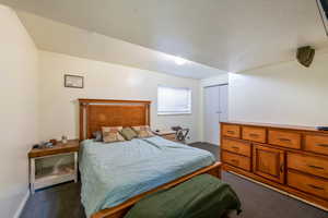 Carpeted bedroom with a textured ceiling and a closet