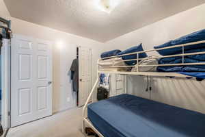 Bedroom with a textured ceiling and carpet floors