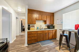 Kitchen with stove, a textured ceiling, dark hardwood / wood-style floors, and sink